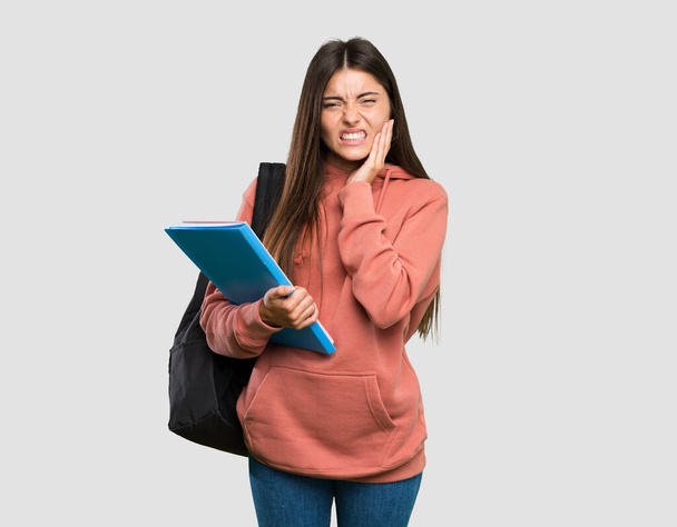 Jeune étudiante tenant des cahiers avec mal de dents sur fond gris isolé
 - Photo, image