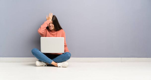 Fiatal tanuló lány egy laptop a padlón, amelyek kétségei összekeverik arckifejezés - Fotó, kép