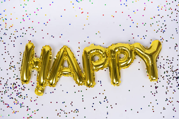Happy letters of frustrated golden balloons isolated with colorful confetti on white background. Congratulations. - Valokuva, kuva