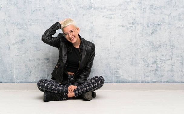 Young woman sitting on the floor smiling - Photo, Image