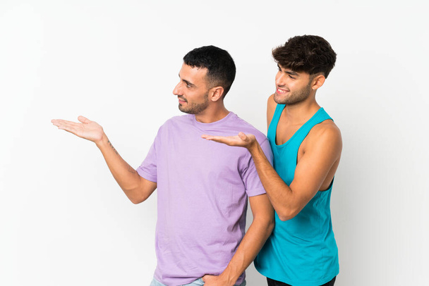 Deux hommes sur fond isolé pointant vers l'arrière et présentant un produit
 - Photo, image