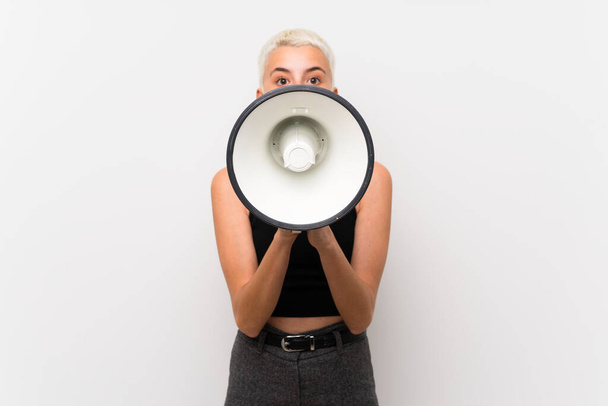 Tiener meisje met kort haar over witte muur schreeuwen door een megafone - Foto, afbeelding