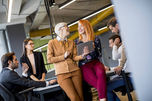 Щасливі ділові жінки працюють разом онлайн на цифровому планшеті перед молодою командою в офісі
 - Фото, зображення