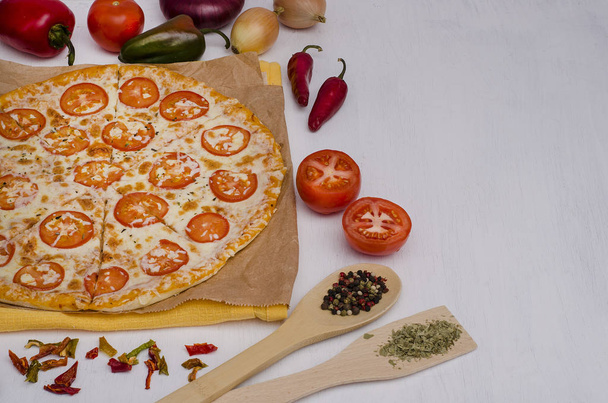 Pizza with cheese and tomatoes with ingredients with copy space on a white wooden background. For menus and advertising pizzerias - Photo, Image