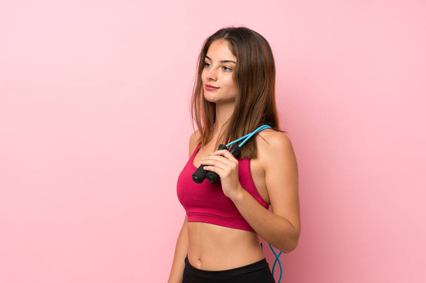 Young sport girl over isolated pink background with jumping rope - 写真・画像