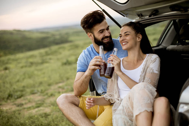 Milující mladý pár sedí v autě trank během výletu v přírodě - Fotografie, Obrázek