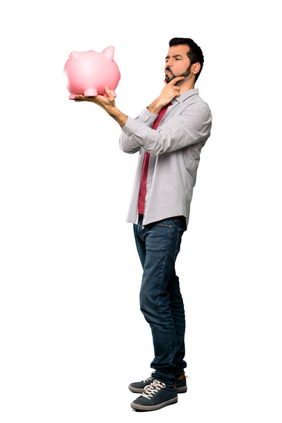 Jóképű férfi szakállal gazdaság egy piggybank - Fotó, kép