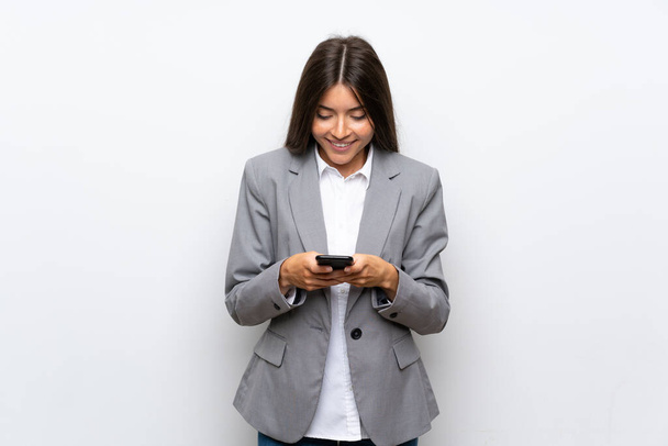 Молодая деловая женщина на изолированном белом фоне отправляет сообщение с мобильного телефона
 - Фото, изображение