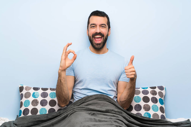 Homem na cama mostrando ok sinal e polegar para cima gesto
 - Foto, Imagem