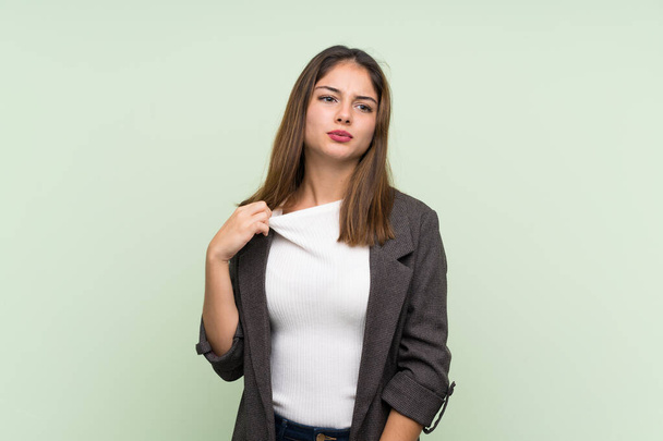Young brunette girl with blazer over isolated green background with tired and sick expression - Foto, Imagen