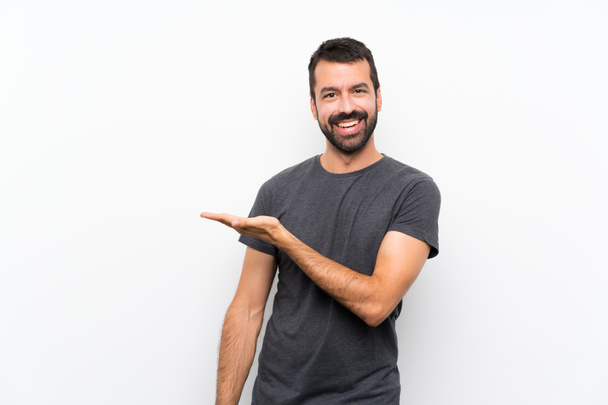 Young handsome man over isolated white background presenting an idea while looking smiling towards - Foto, afbeelding