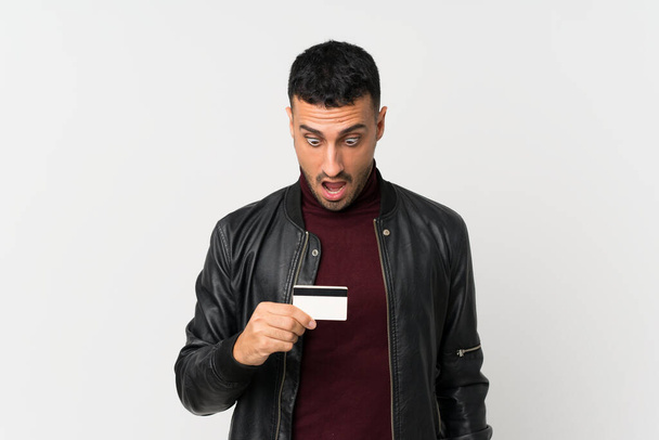junger Mann über isoliertem weißem Hintergrund mit Kreditkarte - Foto, Bild