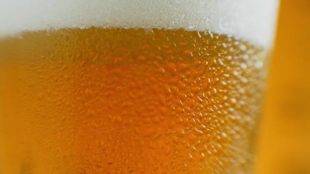 Κοντινό πλάνο αργή κίνηση: κρύα μπύρα σε ένα ποτήρι μεγάλες σταγόνες και φυσαλίδες στην μπύρα. - Πλάνα, βίντεο