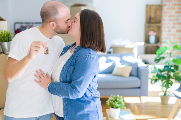 junges Paar lächelt sehr glücklich und zeigt Schlüssel für neues Zuhause, Umzug und Kauf neuer Appartements - Foto, Bild