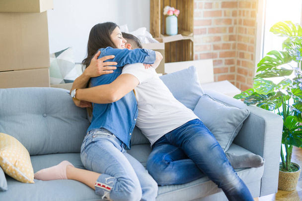 Пара обнимается на диване, счастливо улыбается и радуется новому дому
 - Фото, изображение