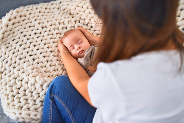 Young beautifull woman and her baby on the sofa over blanket at home. Newborn and mother relaxing and resting comfortable - Fotografie, Obrázek