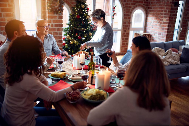Rodzina i przyjaciele jadalnia w domu świętując Wigilię Bożego Narodzenia z tradycyjnym jedzeniem i dekoracji, przygotowanie indyka do kolacji - Zdjęcie, obraz
