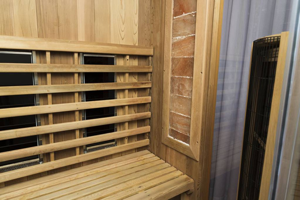 Infrared sauna interior close up view. Wooden walls and bench, ceramic heaters. Healthy lifestyle concept. - Photo, Image
