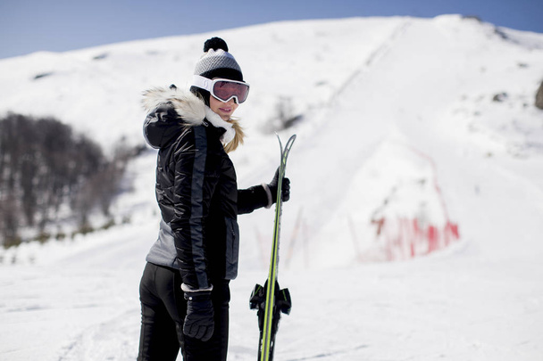 Щаслива молода жінка з лижним спорядженням проводить зимові канікули на гірському курорті
 - Фото, зображення
