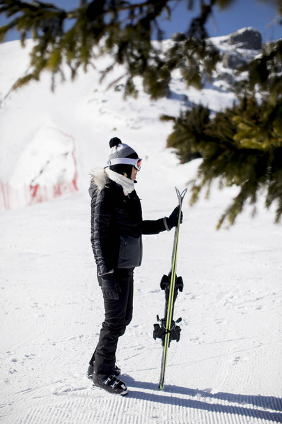 Щаслива молода жінка з лижним спорядженням проводить зимові канікули на гірському курорті
 - Фото, зображення