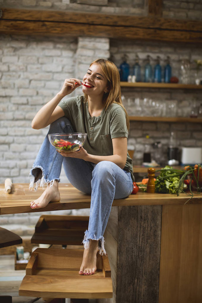 Young woman  eating vegan meal and detox food in the rustic kitchen - Foto, Imagem