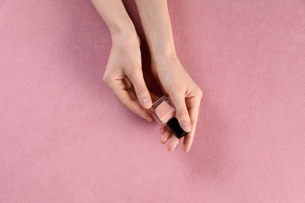 Woman with nail polish on pink fabric, closeup of hands - Фото, изображение