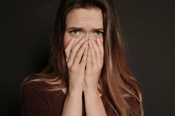 Portrait of upset young woman on dark background - Foto, Imagem