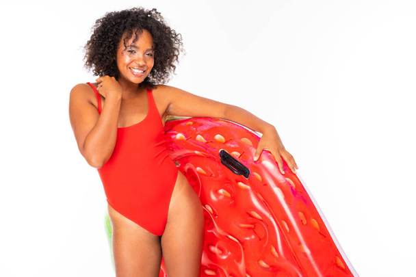 Afrikanerin in Badebekleidung posiert mit Luftmatratze vor weißem Hintergrund  - Foto, Bild