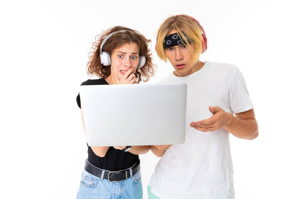 Γυναίκα και άνδρας ποζάρουν σε ακουστικά με laptop σε λευκό φόντο   - Φωτογραφία, εικόνα
