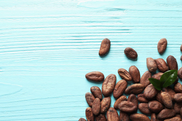 Tasty cocoa beans on blue wooden table, top view. Space for text - 写真・画像