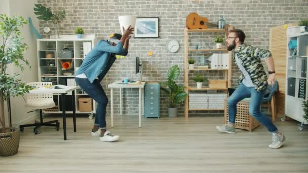 Empresarios emocionados jugando juego en la oficina tirando papel en la cesta riendo
 - Metraje, vídeo
