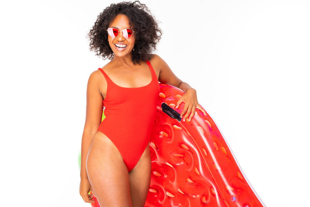 Afrikanerin in Badebekleidung posiert mit Luftmatratze vor weißem Hintergrund  - Foto, Bild