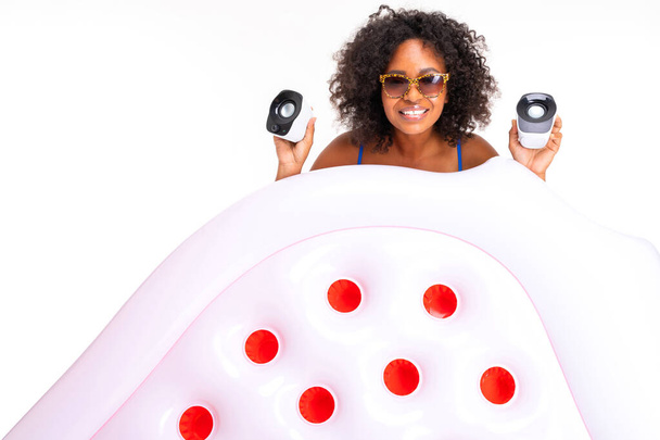 Afrikanerin in Badebekleidung posiert mit Luftmatratze und Lautsprechern vor weißem Hintergrund  - Foto, Bild