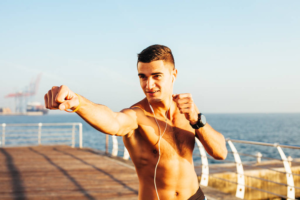 Deportivo chico boxeo en el entrenamiento junto al mar
 - Foto, Imagen