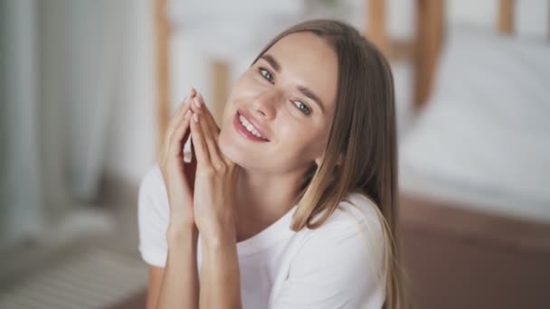 Portrait of beautiful young woman sitting on bed, looking at camera, smiling - Imágenes, Vídeo