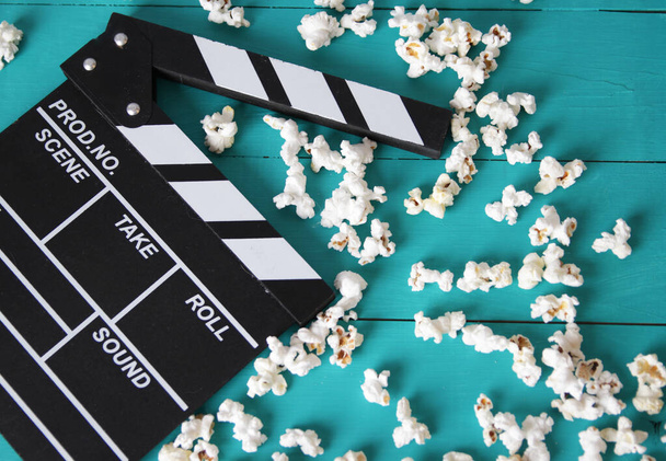 popcorn su sfondo blu in legno, vista dall'alto, accanto a un numeratore di flapper per film
 - Foto, immagini