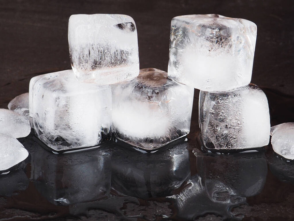кубики льда на фоне черного стола с капельками воды
. - Фото, изображение