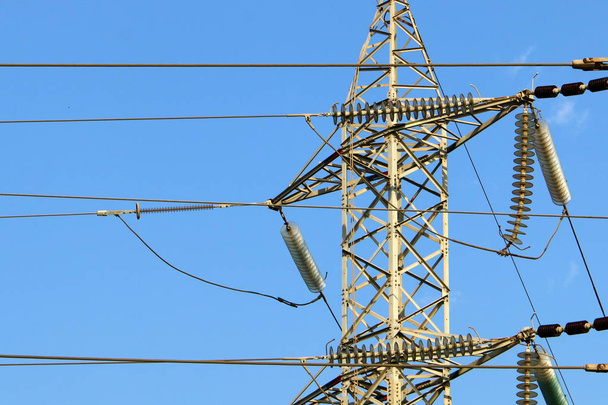 hohe Metallstütze, an der Drähte hängen, durch die elektrischer Strom fließt  - Foto, Bild