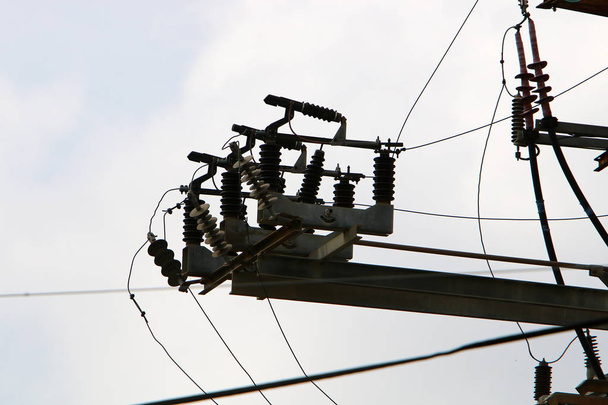 hohe Metallstütze, an der Drähte hängen, durch die elektrischer Strom fließt  - Foto, Bild