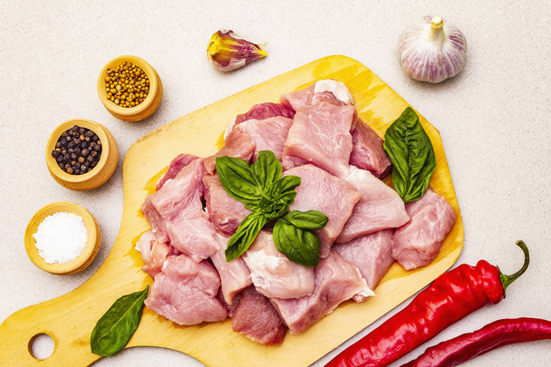 Pescoço de porco cru, cortado em pedaços com legumes frescos e especiarias secas
 - Foto, Imagem