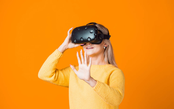 Computer game player uses virtual reality. A young woman in a virtual reality helmet - Zdjęcie, obraz