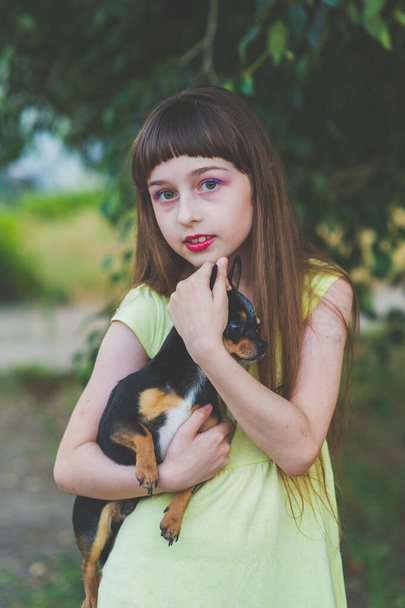 Gün batımında elinde chihuahua köpeği olan küçük bir kız. Bir kızın ellerinde bir köpek yavrusu - Fotoğraf, Görsel