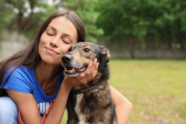 Female volunteer with homeless dog at animal shelter outdoors - Φωτογραφία, εικόνα