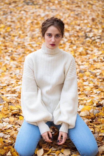 Young beautiful girl in blue jeans and gwhite sweater  - 写真・画像