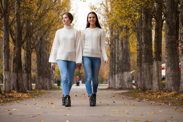 Two girlfriends in a white woolen sweater and blue jeans  - Foto, imagen