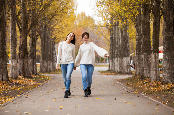 Two girlfriends in a white woolen sweater and blue jeans  - Photo, Image