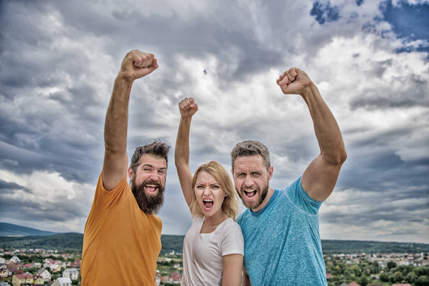 Ways to build ohesive team. Woman and men look confident successful sky background. Threesome stand happy confidently with raised fists. Behaviors of cohesive team. Celebrate success. Yes we can - Valokuva, kuva