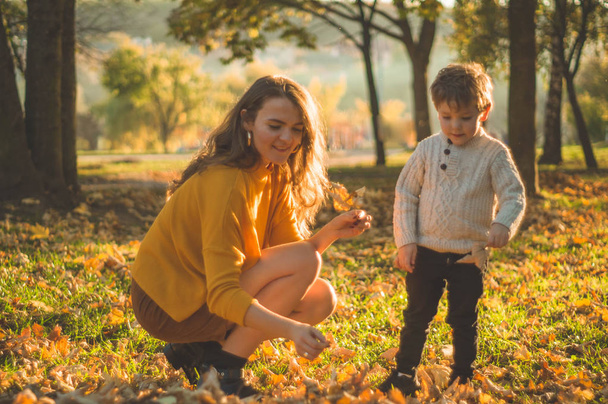 Anne ve oğlu parkta yürüyor ve güzel sonbahar doğasının tadını çıkarıyorlar. - Fotoğraf, Görsel