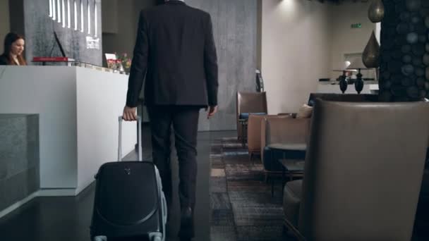 Бизнесмен с дорожным чемоданом прибывает в отель на отдых
 - Кадры, видео