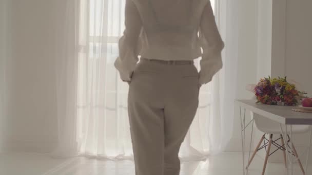Back view of a confident blond businesswoman in official clothes walking to the window and looking out. Rich Caucasian lady spending time indoors alone. - Footage, Video